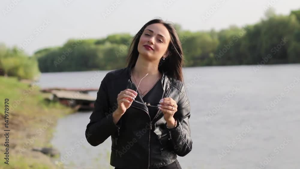 a beautiful brunette wears sunglasses on a river a beautiful brunette wears sunglasses on a river
