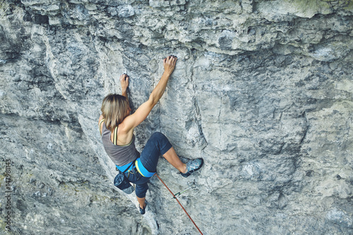 woman rock climber climbs on the cliff. rock climber climbs on a rocky wall. woman makes hard move. top view