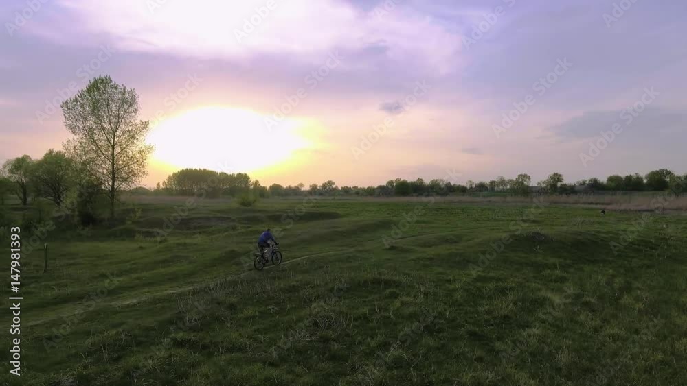 man cyclist rides on the spring green meadow man cyclist rides on the spring green meadow