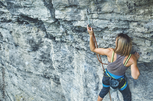 woman rock climber climbs on the cliff. rock climber climbs on a rocky wall. woman makes hard move. top view