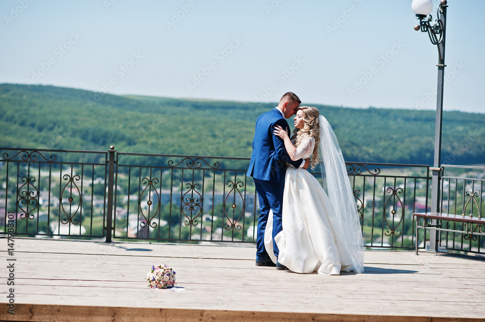 Happy wedding couple in love at observation deck on sunny day.