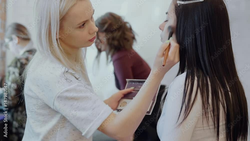 Make up artist applying face powder to a customer in a beauty store Make up artist applying face powder to a customer in a beauty store