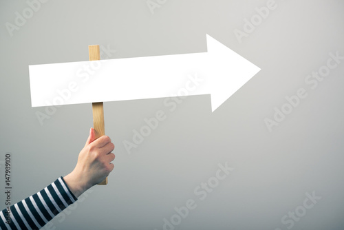 Woman holding guiding direction arrow sign photo