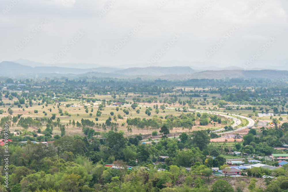Curve road, Village and town surrounded by countryside with mountain background in central of Thailand.