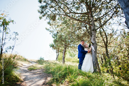 Happy wedding couple in love on sunny day stay near trees. © AS Photo Family