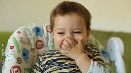 Cute baby boy sitting in the highchair and eating snacks
