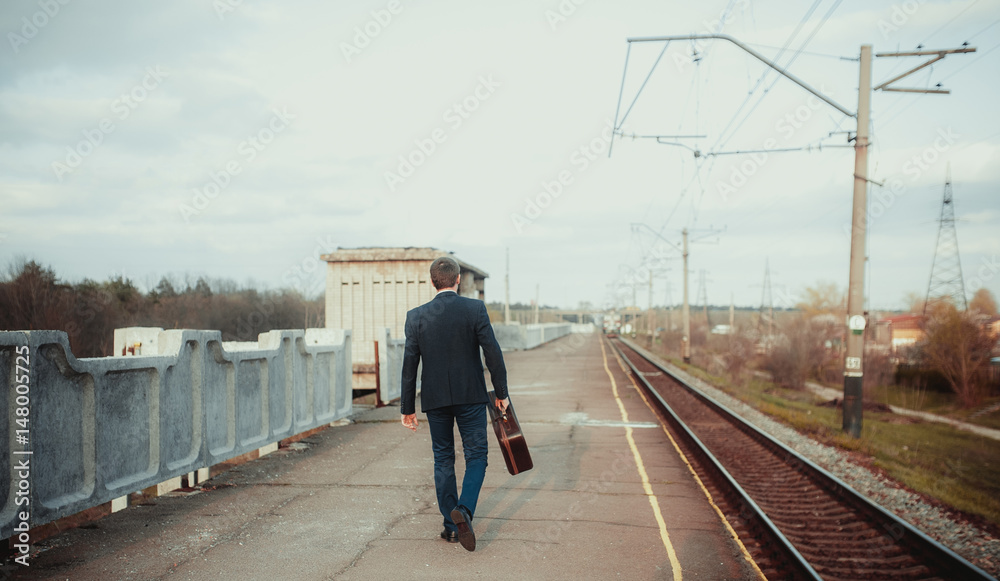 Business trip. Businessman in suit with suitcase walks along the platform station. Traveling salesman.
