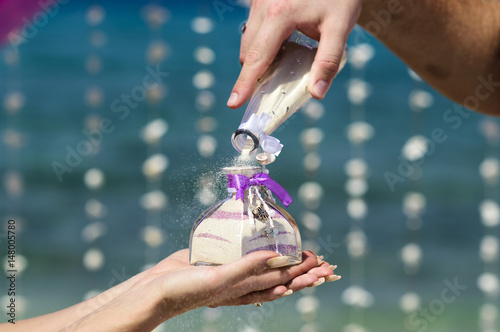 Accessory kit bottles with sand for a wedding is on the table on the coastline of caribbean sea