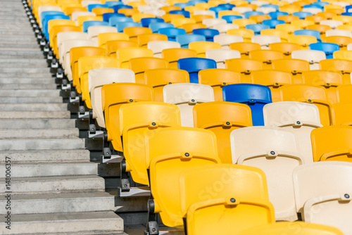 rows of yellow and blue stadium seats and stadium stairs