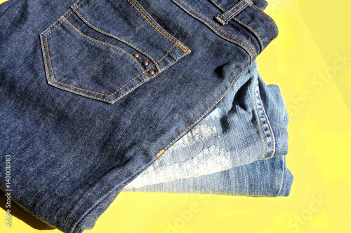 jeans laid in a pile on a yellow background
