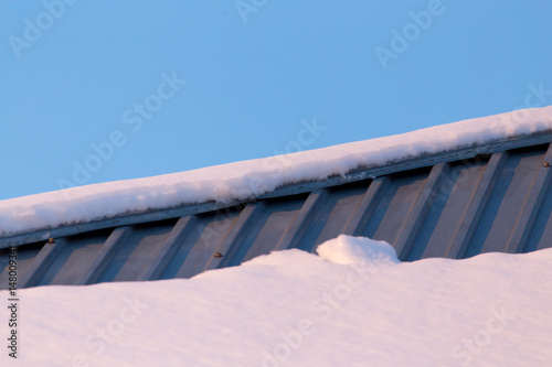 Snow on the roof of the house at sunset