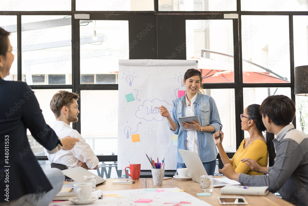 © ChayTee - Young asian charming woman making presentation about new idea by brainstorming meeting in modern office.