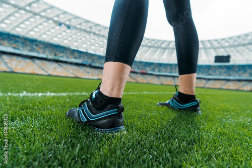 Close-up partial view of sportswoman standing on soccer stadium grass