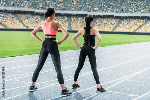 Athletic young women in sportswear exercising on running track stadium