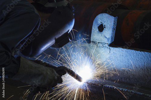 Worker welding steel by MIG/MAG weld (Argon welding) in industrial factory.