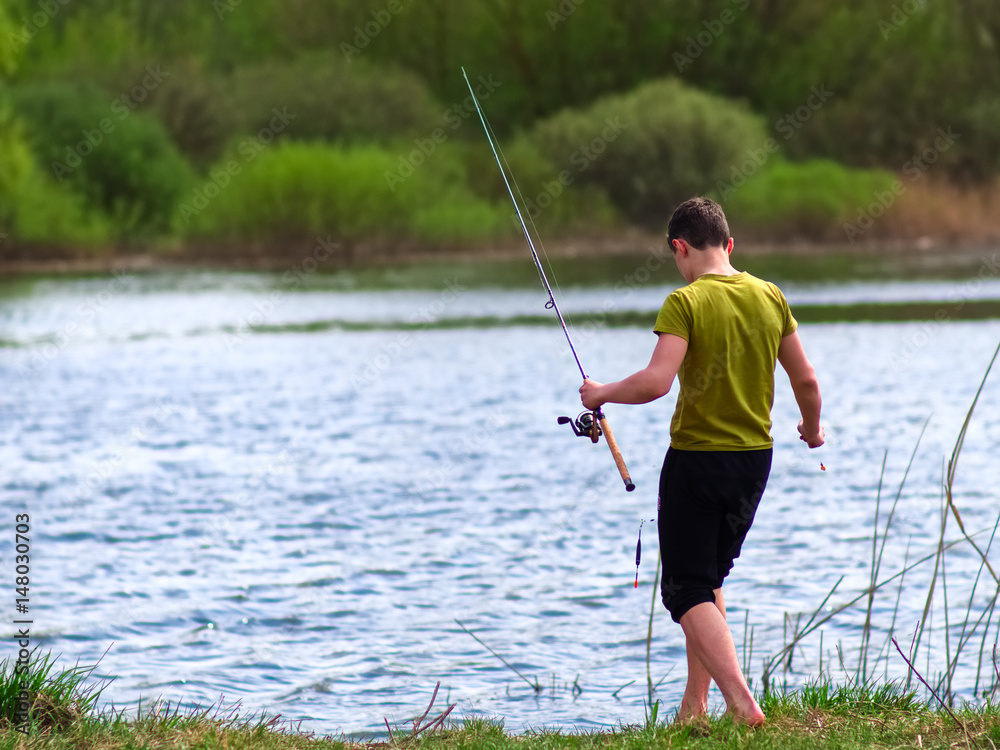 Teenager catches fish on the river Teenager catches fish on the river