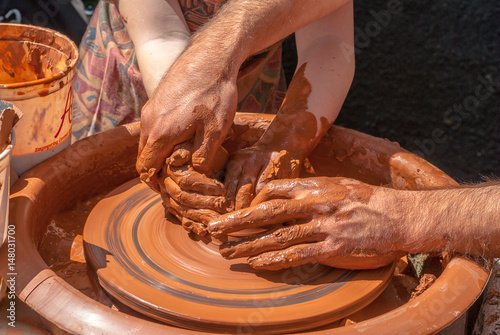potter teaches to sculpt in clay pot on a turning pottery wheel