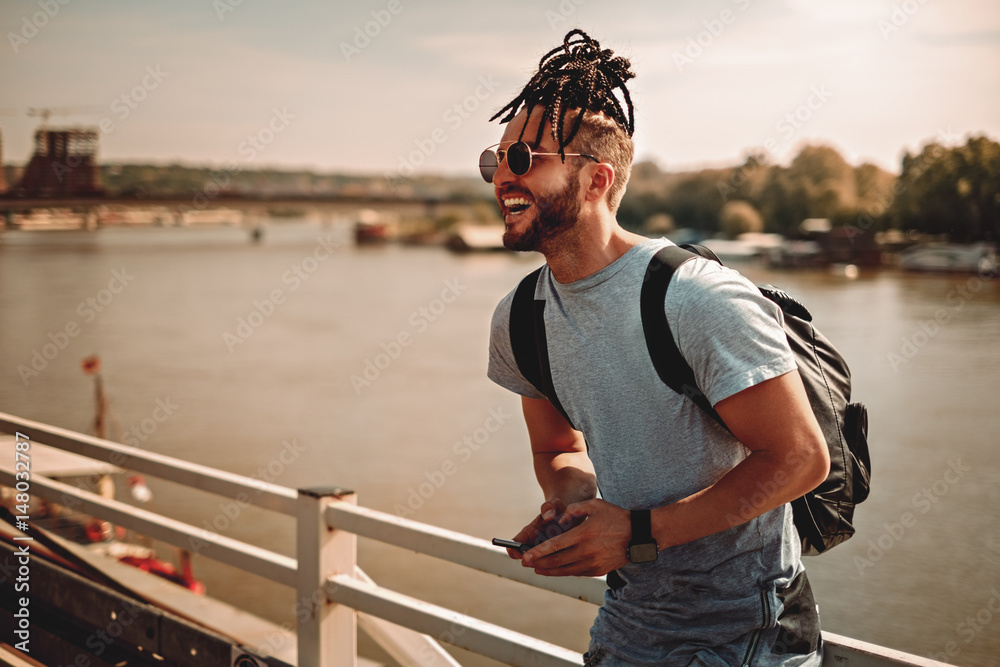 Man with dreadlocks using phone by the river