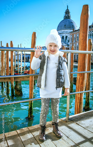 child on embankment in Venice, Italy in winter handwaving photo