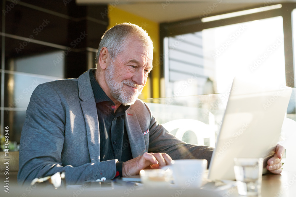 Senior businessman working on laptop in cafe Senior businessman working on laptop in cafe