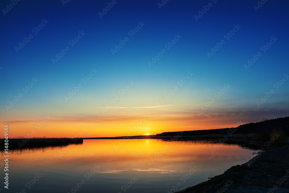 sunset in blue sky over river