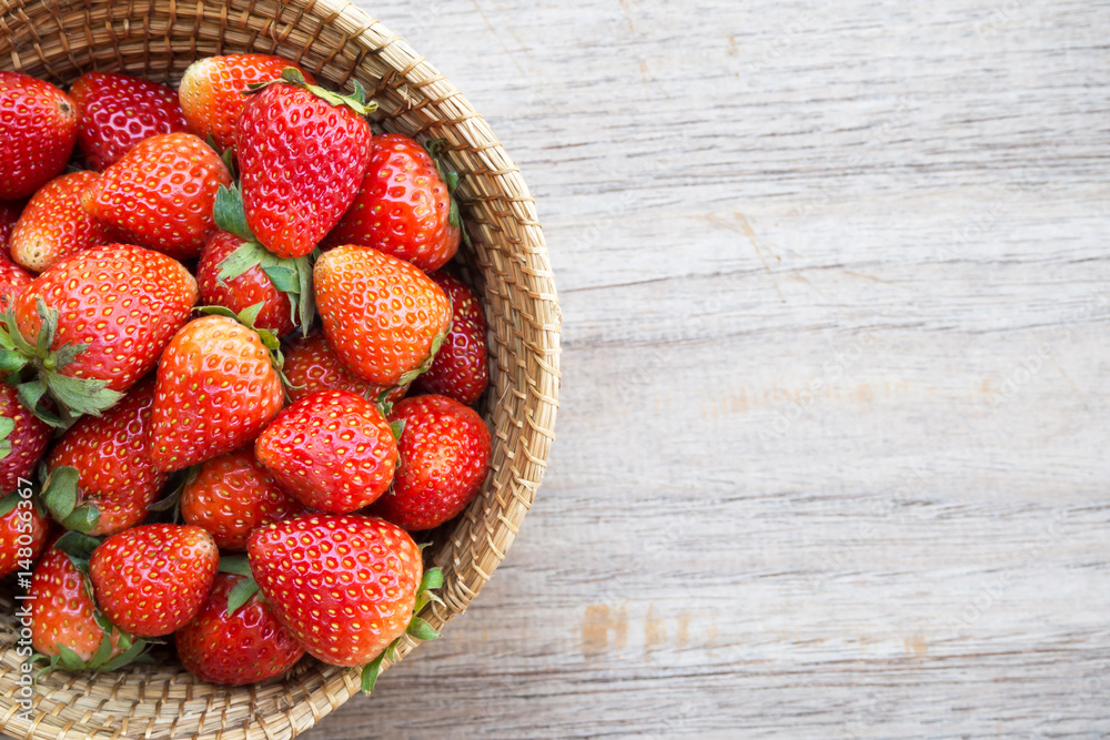 Fresh strawberries in bamboo basket on wooden background. Top view. Favorite fruit for valentine. Sweet and freshness tasty. 
