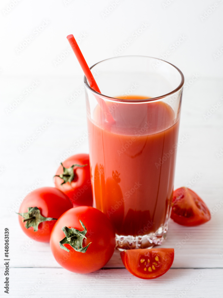 Tomato juice in glass and fresh tomatoes on white wooden table. Tomato juice in glass and fresh tomatoes on white wooden table.