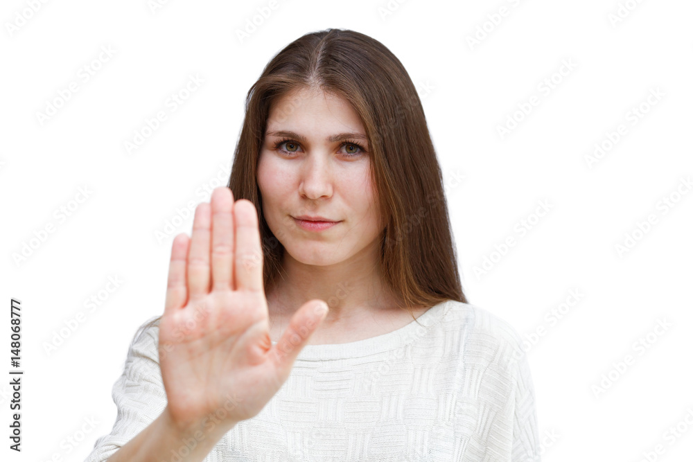 Portrait of a young brunette woman in a light jumper looking directly at the camera and showing stop gesture isolated on white background. Focus on the face. Demonstration of various emotions. Portrait of a young brunette woman in a light jumper looking directly at the camera and showing stop gesture isolated on white background. Focus on the face. Demonstration of various emotions.