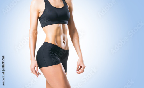 Fit, healthy and sporty woman in sportswear over blue background.