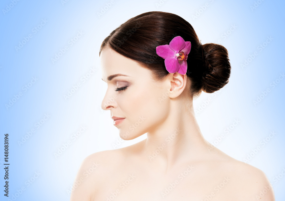 Close-up portrait of a beautiful girl with an orchid flower in her hair. Health, treatment, spa concept. Close-up portrait of a beautiful girl with an orchid flower in her hair. Health, treatment, spa concept.