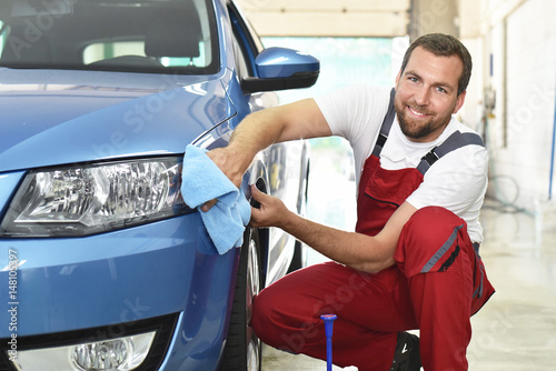 professionelle Autoreinigung in einer Werkstatt - Mann poliert Lack eines Fahrzeuges // Professional car cleaning in a workshop - man polishing paint of a vehicle photo