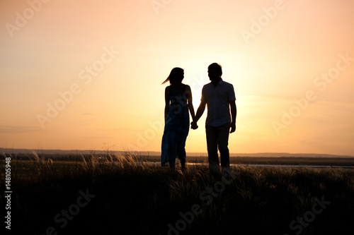 Young couple walking forward to sunset