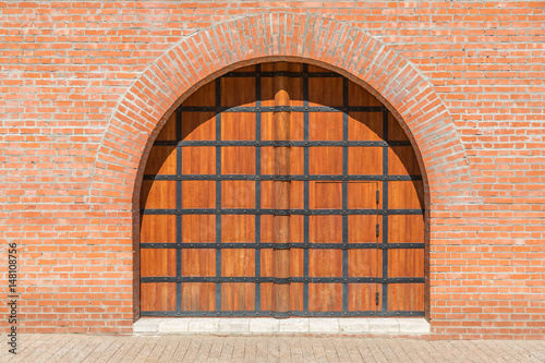 . A wooden gate with a door in the brick wall. Space to insert text.