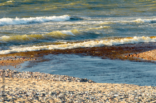 Small river goes into the sea. Waves in the background. photo