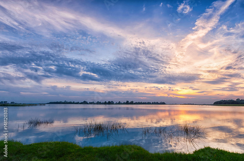 Nature background sunset over the river and beautiful sky with reflection in the water.