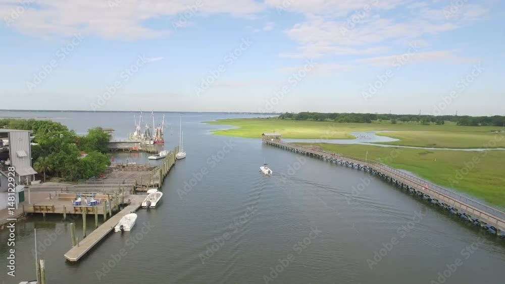 Boating on the water in a creek with docks and a marsh nearby. Boating on the water in a creek with docks and a marsh nearby.
