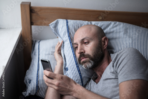 Mid forties depressed man in bed at home photo