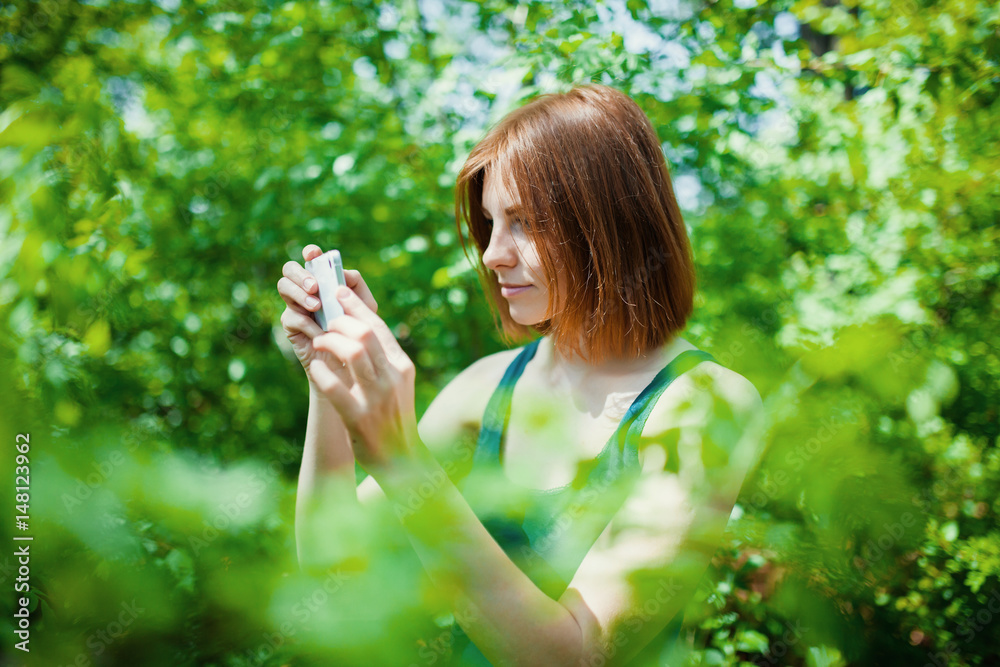 young woman make photo on cellphone, spring flowers background young woman make photo on cellphone, spring flowers background