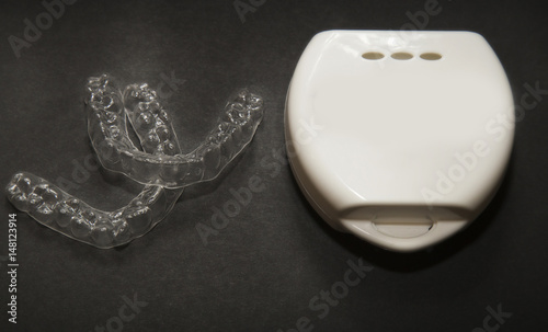 Isolated transparent teeth prosthesis with its box over black for design