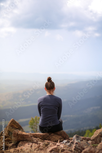 Young pretty woman sitting at the top of the mountain