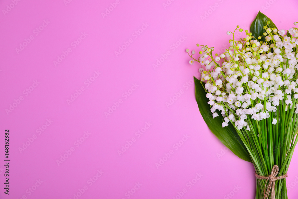 Bouquet of white lilies of the valley on a pink surface
