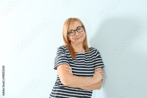 Happy senior woman in eyeglasses on light background