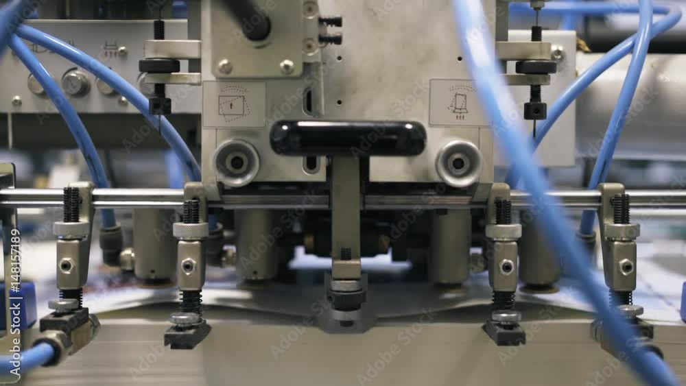 Close up of a printing plant machine with wires and gears during its work process. Locked down real time close up shot Close up of a printing plant machine with wires and gears during its work process. Locked down real time close up shot