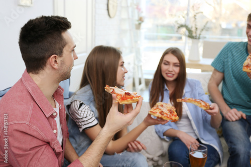 Friends eating tasty pizza at home party