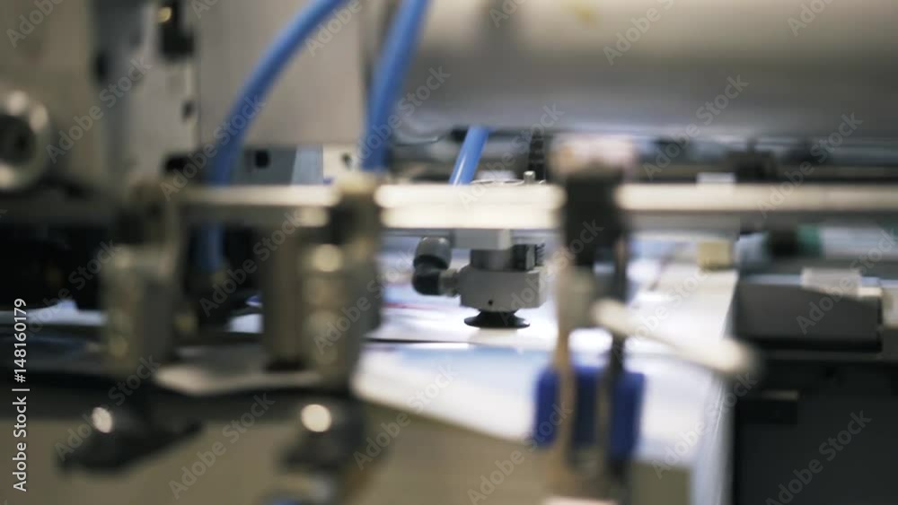 Close up of a printing plant machine insides with wires and gears during its work process. Left to right pan real time close up shot Close up of a printing plant machine insides with wires and gears during its work process. Left to right pan real time close up shot