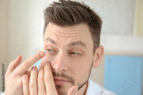 Young man putting contact l...