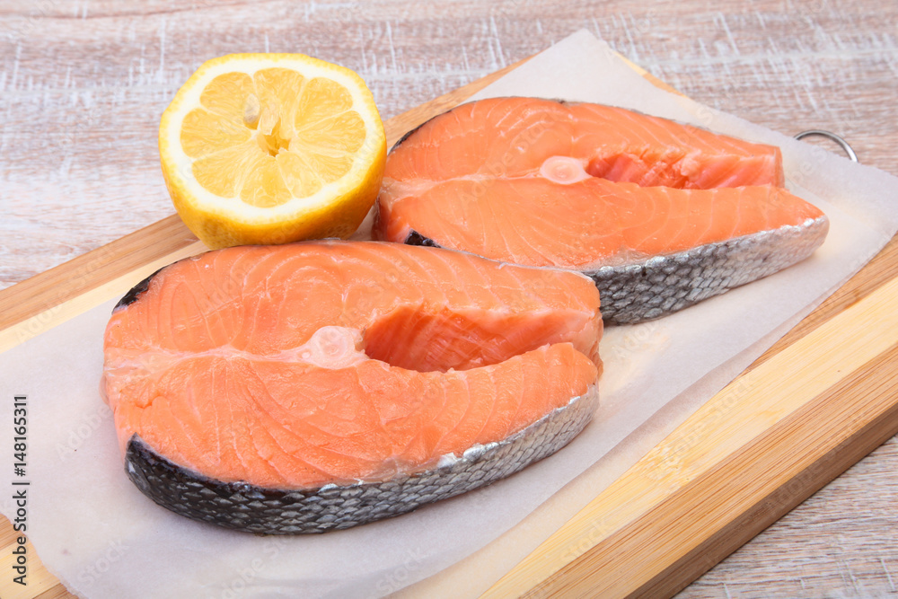 fresh raw salmon with spices and lemon on wooden cutting board. ready for cookin fresh raw salmon with spices and lemon on wooden cutting board. ready for cookin