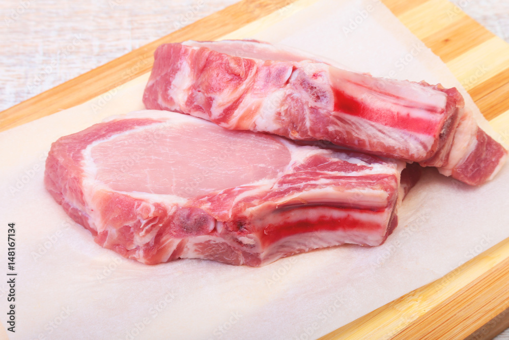 Raw pork chops, spices on cutting board. Ready for cooking.