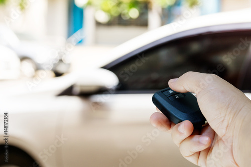 Holding car remote with blur car background.