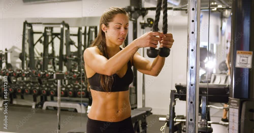 Well trained woman workout triceps muscles pulling cable machine in gym Well trained woman workout triceps muscles pulling cable machine in gym